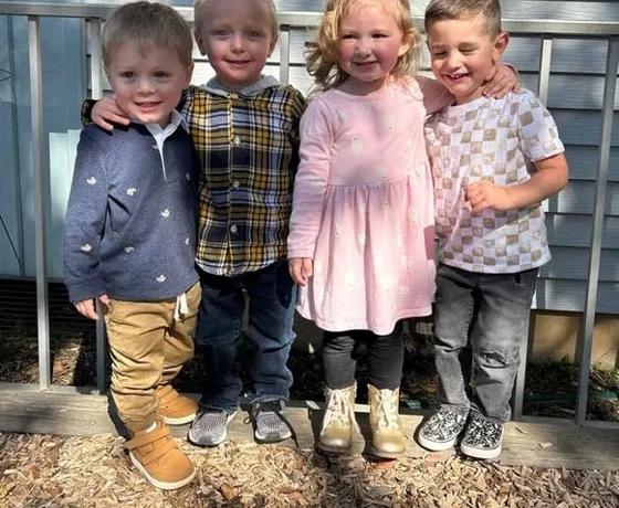 Four young friends standing together outside on the playground